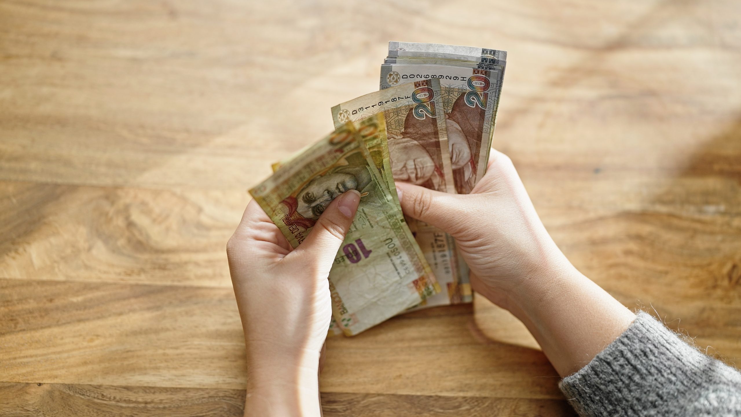 hands,of,woman,counting,peruvian,soles,banknotes,at,room